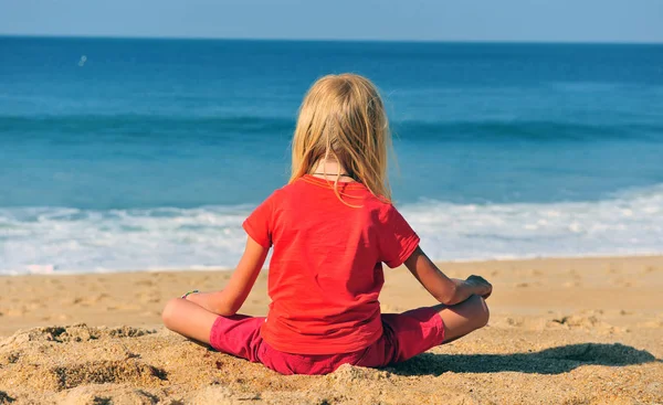 Děcko, co sedí u moře na písečné pláži — Stock fotografie
