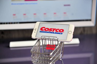 Alışveriş sepetinde cep telefonu Costco Toptan logosu.