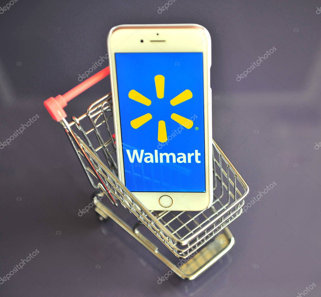 YAROSLAVL, RUSSIA - AUGUST 13, 2019: iPhone with Walmart logo in mini shopping cart on table.