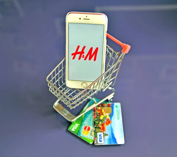 桌上配有 H&M 徽标和信用卡的智能手机 — 图库照片