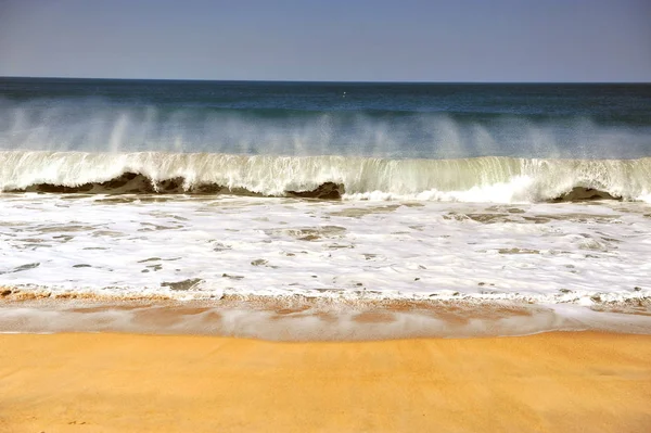 Vågor på Nazare sandstrand med stormiga himlen — Stockfoto