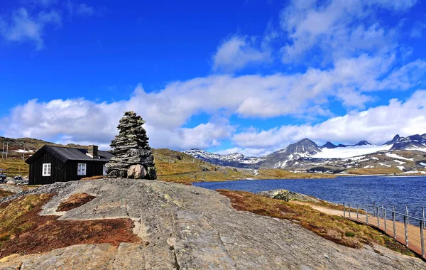 Paysage naturel avec maison en bois noir et pyramide de pierres — Photo