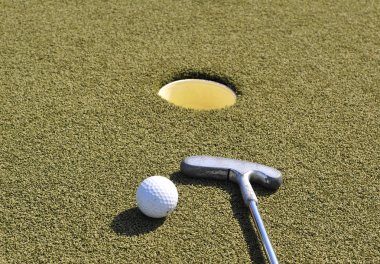Mini golf sopası ve top delikte.