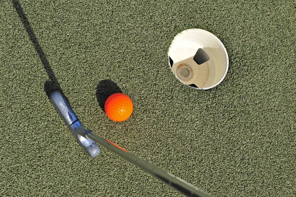 Top view of mini golf equipment: stick, ball and court