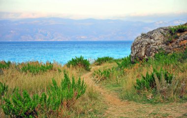 Dağlı ve arka planda deniz olan güzel bir yol.