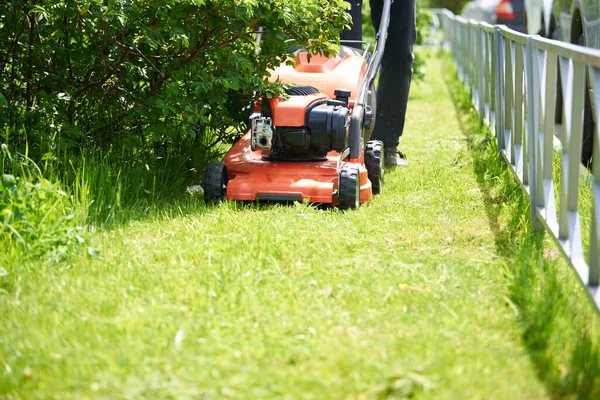 A close-up lawnmower mows the green grass on the lawn.Bright Sunny day — Stock Photo, Image