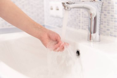 Elini yıkıyor. Yürüyüşten sonra ellerini yıkıyor.