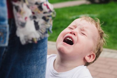 Çocuk annesinin ayaklarının dibinde ağlıyor. Duygusal bir fotoğraf. Üzgün çocuk.