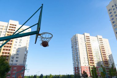 Bir basketbol sepeti ve modern konut binalarının arka planında sokak basketbolu için bir kalkan. Topla temiz hava egzersizi yap. Basketbol antrenmanı.