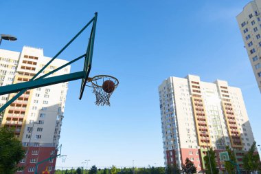 Bir basketbol sepeti ve modern konut binalarının arka planında sokak basketbolu için bir kalkan. Topla temiz hava egzersizi yap. Basketbol antrenmanı.
