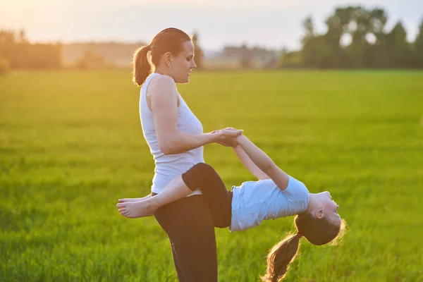 Uma mãe e seu filho fazem ioga ao ar livre. O conceito de um estilo de vida saudável. Recreação ao ar livre. Aulas de meditação e ioga — Fotografia de Stock