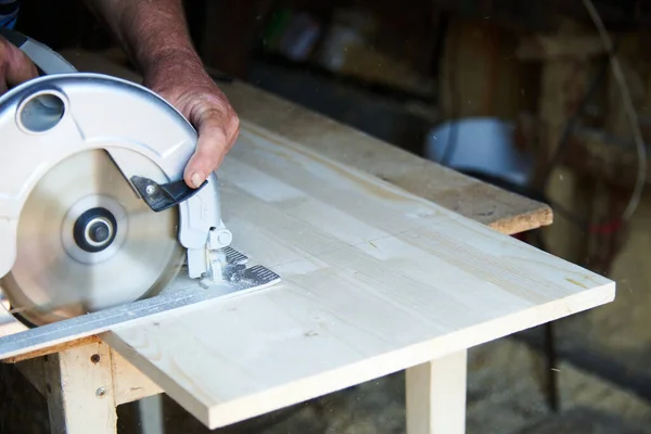 Un operaio che utilizza una sega circolare lavora con il legno in un laboratorio di falegnameria — Foto Stock