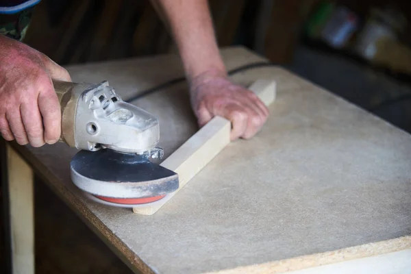 Un lavoratore che utilizza una levigatrice lavora con il legno in un laboratorio di falegnameria — Foto Stock