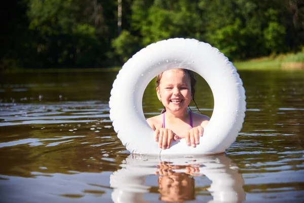 Dziecko z kółkiem kąpie się w jeziorze. Dziecko wpada do wody, gotowe do pływania. Koncepcja rekreacji na świeżym powietrzu z dziećmi. Uczyć dziecko pływać — Zdjęcie stockowe