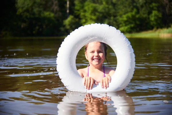 Dziecko z kółkiem kąpie się w jeziorze. Dziecko wpada do wody, gotowe do pływania. Koncepcja rekreacji na świeżym powietrzu z dziećmi. Uczyć dziecko pływać — Zdjęcie stockowe