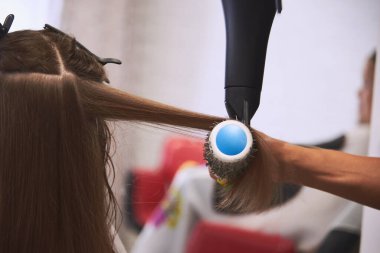 Berber dükkanında saç kurutma makinesiyle kurutuluyor. Usta evrensel kuru ve saçlarını tara