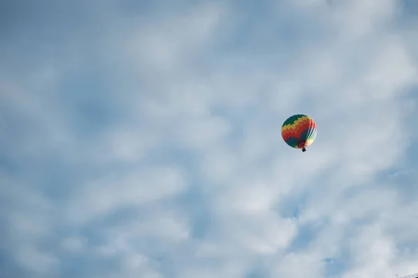 Jeden pestrobarevný balón letí vysoko na obloze pokrytý mraky — Stock fotografie