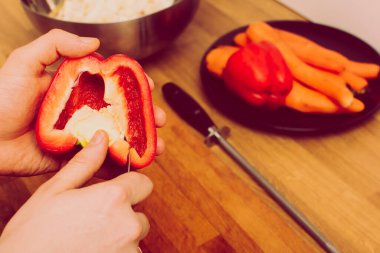 Kırmızı biber ya da kırmızı biber tutan bir adam. Sağlık ve sağlıklı yaşam tarzı kavramı. Adam tohumları elde etmek için kırmızı dolma biberi bıçakla kesiyor. Eski, eski, eski tarz. Adım adım.