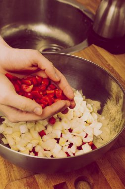 Adam, doğranmış soğanın olduğu metal kaseye kırmızı biber ekliyor. Eski, eski, eski tarz.