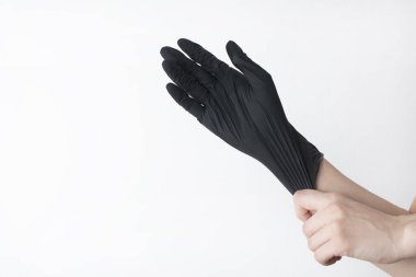 Doktorun siyah eldivenleri ya da beyaz arka planda saç stilisti. Eldivenler koluna takılmış..