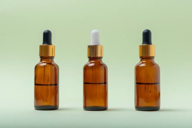 Cam kozmetik kahverengi şişeleri ve nane arkaplanlı pipeti.