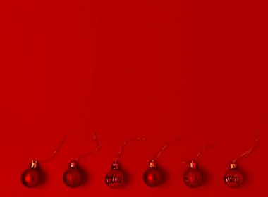 Kırmızı arka planda kırmızı Noel süslemeleri. Toplar çerçevenin altında. Mesaj için yer. Asgari.