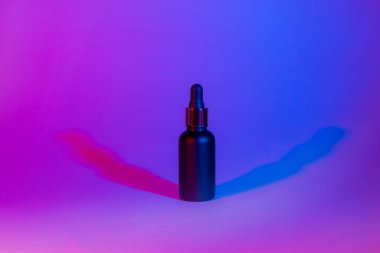 Neon rengi arka planda bir şişe siyah mat rengi. Kozmetik konsepti. En düşük