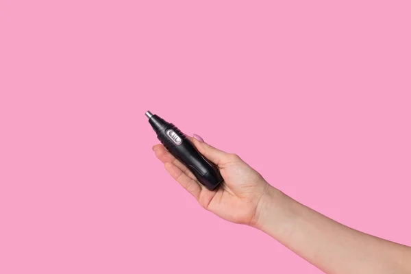 Kadın eli, erkeğin elektrikli maşasını nazikçe tutar. Pastel pembe arka planda minimalizm