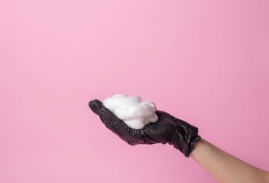 Siyah eldivenli stilistin elinde bir saç fırçası var. İkinci el köpüğü alır. saç bakım konsepti