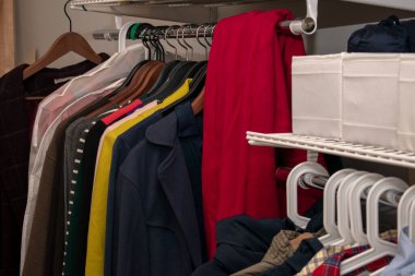 Askılarda ve konteynırlarda rengarenk giysiler var. Depolama sistemini aç. yatay resim.