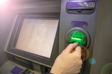 Kız ATM 'ye bir kart sokuyor. Yakın plan. Mevduat ve tasarruf kavramı.
