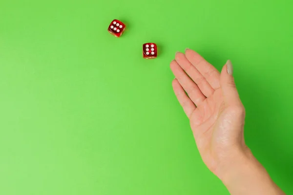 female hand rolling red dice isolated on green background.