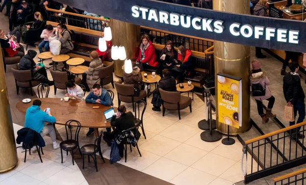 Mart 2019. Saint Petersburg, Rusya. Galeride Starbucks 'ın fotoğrafı. İnsanlar masalara oturur ve işlerine bakarlar. Yukarıdan görüntüle