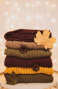 Parlayan bir çelengin arka planına karşı bir yığın sıcak örülmüş vintage süveter. Sonbahar konsepti
