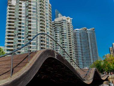 Toronto, Ontario, Kanada, 11 Ekim 2019, Toronto su cephesi, aşağı kasaba bölgesi, güneşli sonbahar gününde arka planda modern apartman binaları olan dalgalı ahşap bir köprü manzarası.