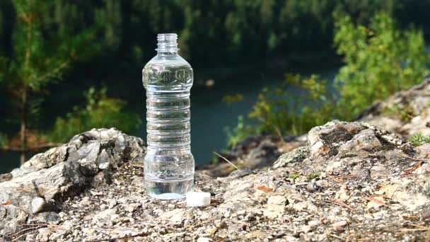 Fles van schoon water staat op een rots, op berggebied. Thema gezondheid en ecologie — Stockvideo