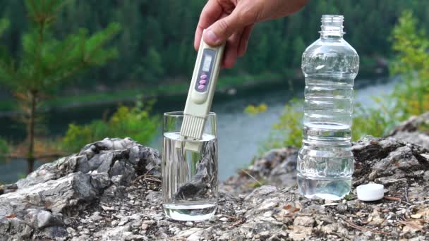 El hombre hace la medición de sales de PPM en un vaso de agua limpia en la zona de montaña. Tema de salud y ecología. Lento. — Vídeos de Stock