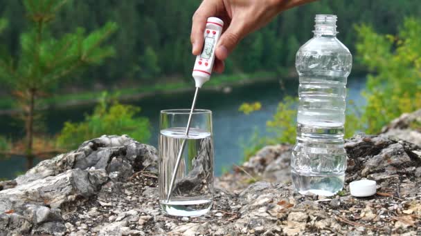 Der Mensch führt Temperaturmessungen in Grad Celsius in einem Glas Wasser in bergigem Gebiet durch. Gesundheit und Ökologie Zeitlupe — Stockvideo