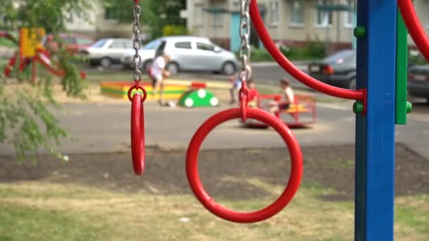 Gymnastiek ringen op de speelplaats in de tuin. Ongericht kinderen op achtergrond — Stockvideo