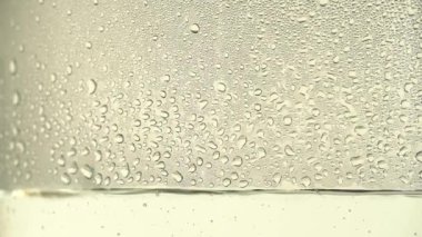 Beyaz zemin üzerinde bir cam kavanoz içinde saf su ya da alkol damla damla. Odak vardiya. Damıtma süreci veya alkol üretimi. Yakın çekim