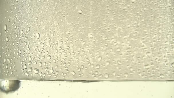 Gotas de agua pura o alcohol gotean dentro de un frasco de vidrio, sobre fondo blanco. Cambios de enfoque. El proceso de destilación o la producción de alcohol. Primer plano — Vídeo de stock