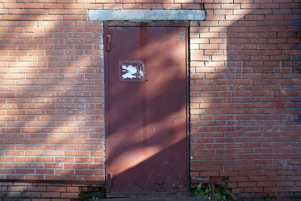 Ziegelmauer mit Zerstörung, mit rostiger Eisentür. Hintergrund der Stadt — Stockfoto