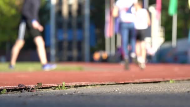 Blurred background of runners on provincial stadium. Amateur sport footage slow — Stock Video