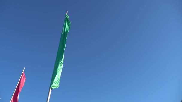 Eine schmale vertikale Fahne weht im Wind gegen den blauen Himmel. Sportaufnahmen 4k — Stockvideo