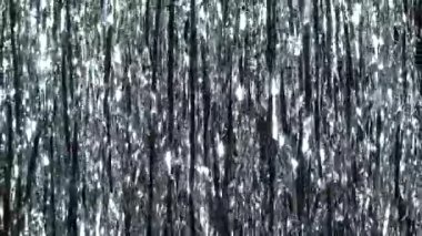 Simli gümüş yağmuru. Parlak ışıklarda ve parlak parçacıklarda dinamik arkaplan. Parlak gümüş parıltılı ışıltılarıyla güzel gümüş bir arka plan. Şenlik havası. Noel ya da tatil teması