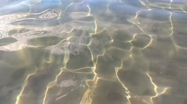 Su dalgalarından yansıyan ışık ve beyaz bulutlar. Su bozulması ve su altında parlak güneş lekeleri.