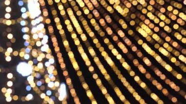 Süslü Noel ağacı, değişken mercek odağı, karanlık arka planda bokeh etkisi. Bir sürü titreyen çelengi olan siluet Noel ağacı. Mutlu Noeller ve mutlu yıllar konsepti. 4K UHD