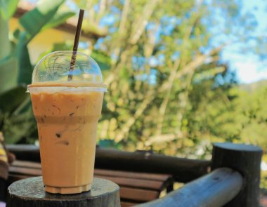 doğal manzaralı ahşap masa üzerinde plastik kap içinde bir taze buzlu kahve 