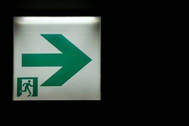 karanlık oda duvar arka plan üzerinde bir acil çıkış yolu tabela.