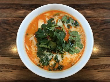 Ahşap masa arka plan üzerinde kırmızı çorba kasesinde Şangay sıcak soslu erişte.